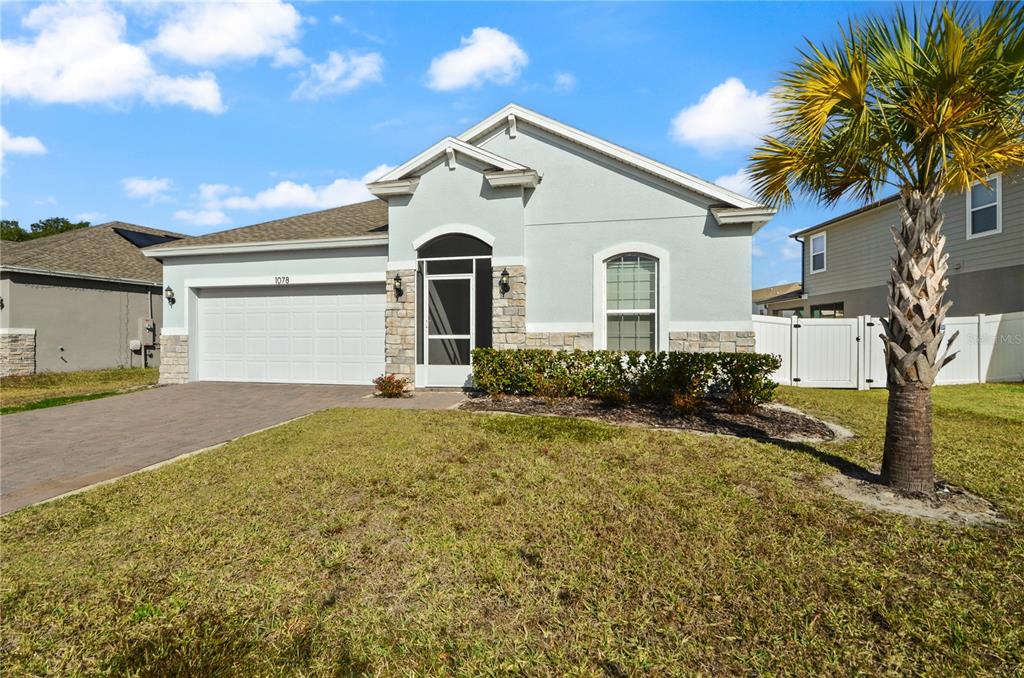 A light blue single-story house with a two-car garage and a palm tree in front — 1078 CHELAN FALLS DRIVE, DELAND, FL