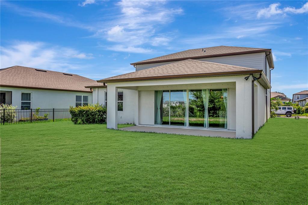 The exterior of a two-story house features a covered patio and a large grassy backyard — 9909 LONGMEADOW AVENUE, PARRISH, FL