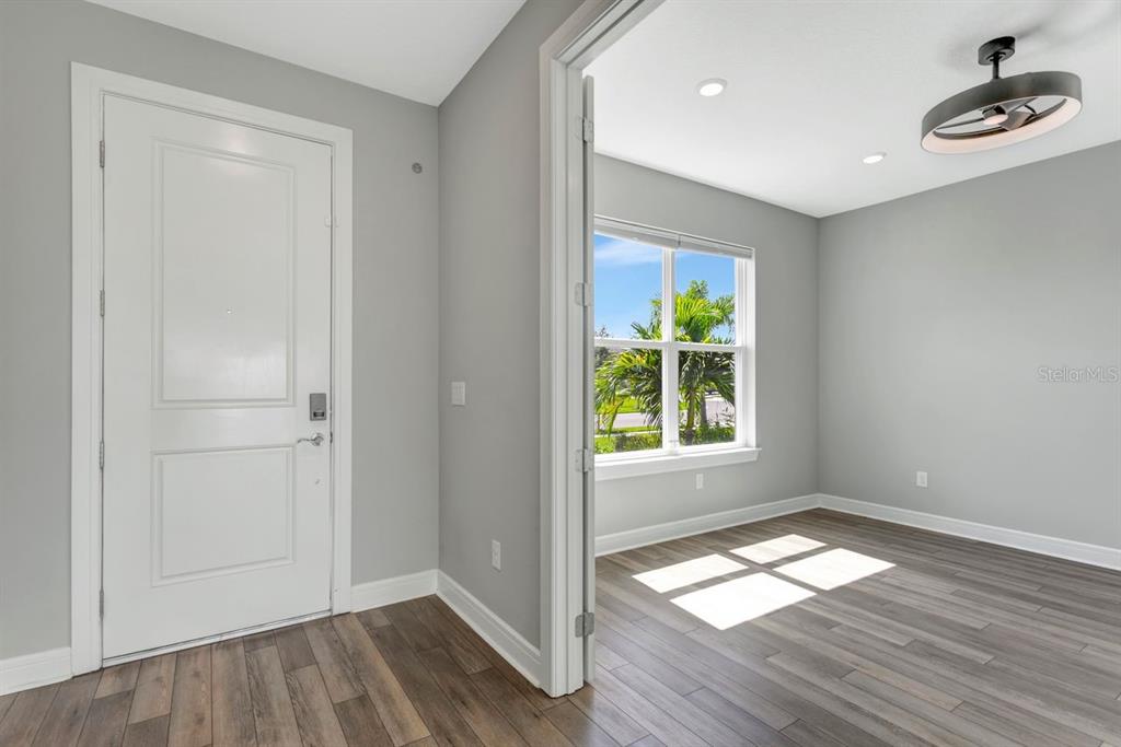 A room with gray walls, wood-look flooring, and an entryway door leading outside — 9909 LONGMEADOW AVENUE, PARRISH, FL