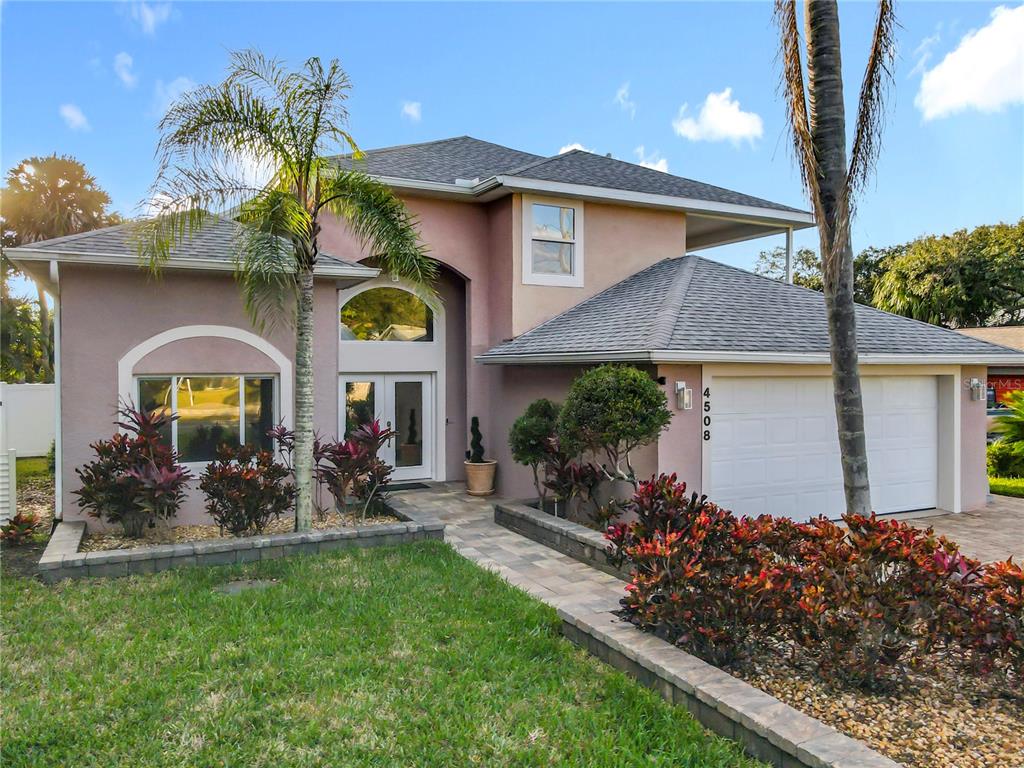 A two-story house with a stucco exterior, a two-car garage, and a landscaped front yard — 4508 SAXON DRIVE, NEW SMYRNA BEACH, FL