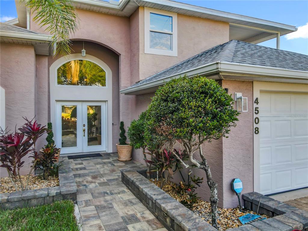 A paved walkway leads to the double front doors of a pink stucco house — 4508 SAXON DRIVE, NEW SMYRNA BEACH, FL