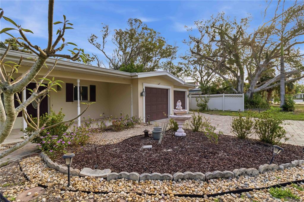A single-story house exterior features a paved driveway, a small fountain, and a landscaped garden — 617 CALLE DE PERU, SARASOTA, FL