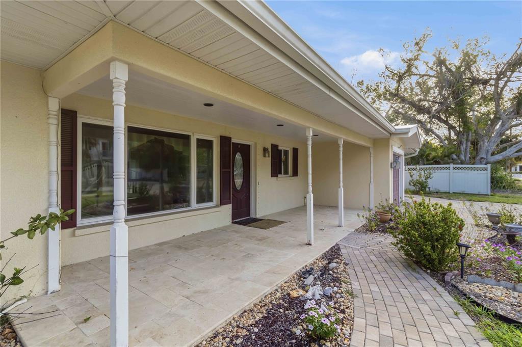 A covered front porch with stone flooring leads to a front door and walkway — 617 CALLE DE PERU, SARASOTA, FL