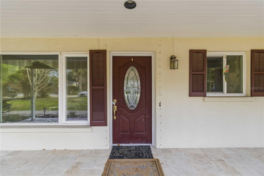 A front porch features a maroon door with a decorative glass oval and brown shutters — 617 CALLE DE PERU, SARASOTA, FL
