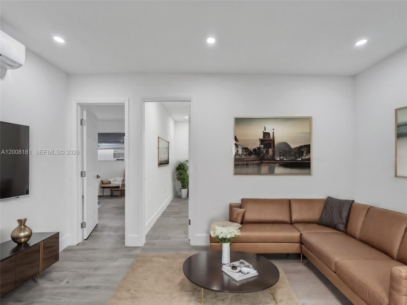 A living room features a brown leather sectional, a round coffee table, and white walls — 5740 Mayo St # 0, Hollywood FL 33023, HOLLYWOOD, FL
