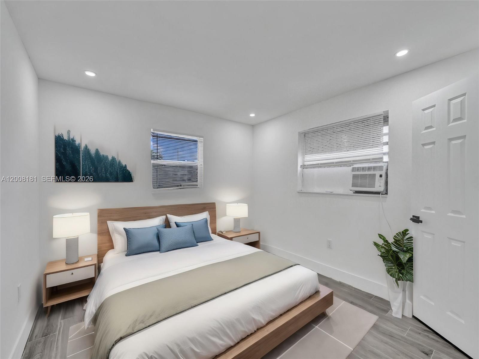 A bedroom features a platform bed, two nightstands with lamps, and a window air conditioner — 5740 Mayo St # 0, Hollywood FL 33023, HOLLYWOOD, FL