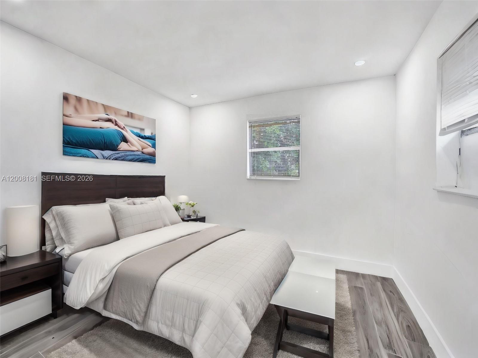 A bedroom features a dark wood headboard, a neutral bedspread, and light wood-look flooring — 5740 Mayo St # 0, Hollywood FL 33023, HOLLYWOOD, FL