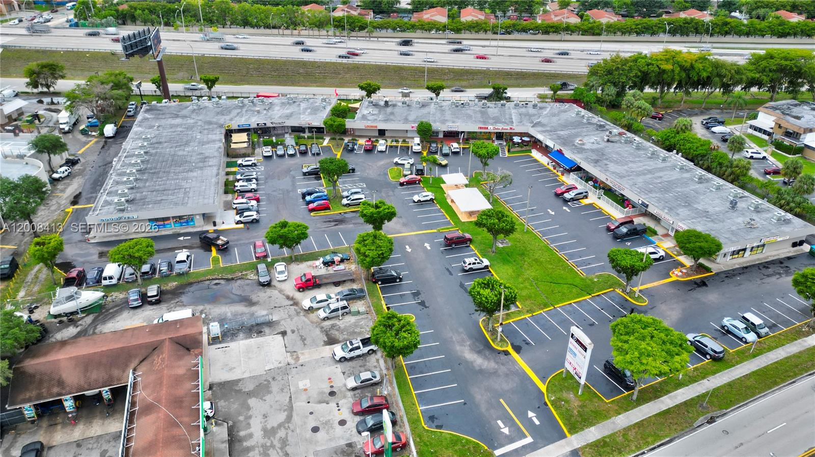 An aerial view shows a commercial strip mall with a parking lot and highway nearby — 68 169 ST, Hialeah FL 33015, HIALEAH, FL