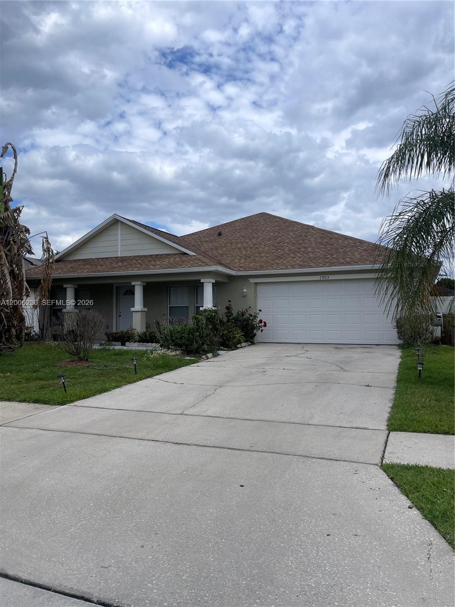 A single-story house with a beige exterior, a two-car garage, and a concrete driveway — 1903 Binnacle, Kissimmee FL 34744, KISSIMMEE, FL