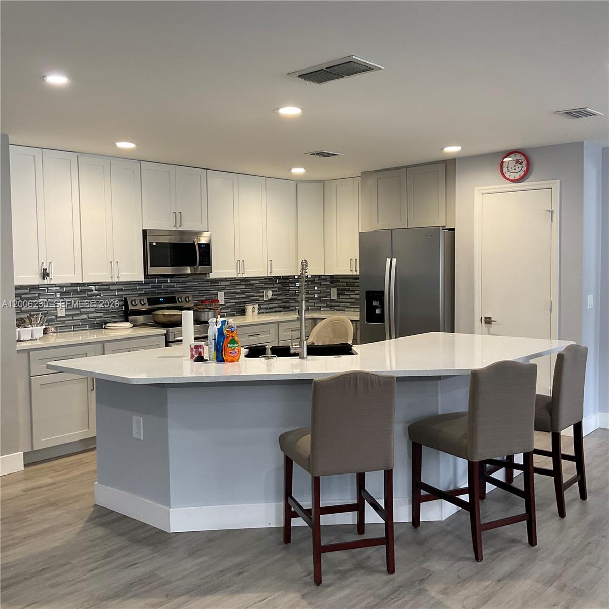 A kitchen features white cabinets, a large island with bar seating, and gray flooring — 1903 Binnacle, Kissimmee FL 34744, KISSIMMEE, FL