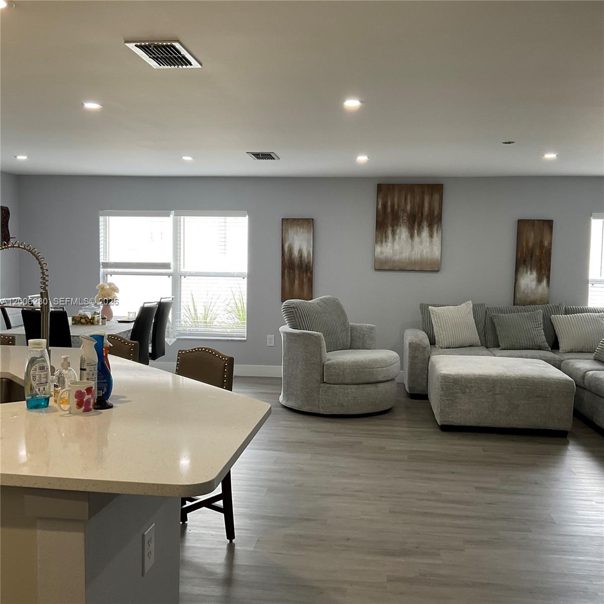 An open-concept living room and kitchen area features light gray walls and wood-look flooring — 1903 Binnacle, Kissimmee FL 34744, KISSIMMEE, FL