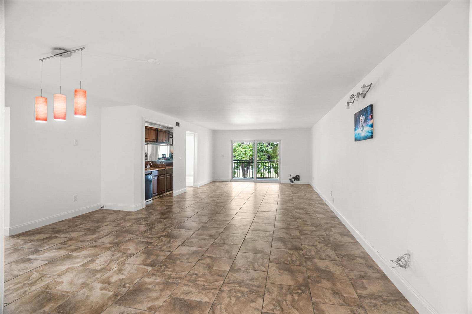 An open-concept living and dining area features tile flooring, white walls, and a sliding glass door — 16141 Blatt Boulevard # 307, Weston FL 33326, WESTON, FL