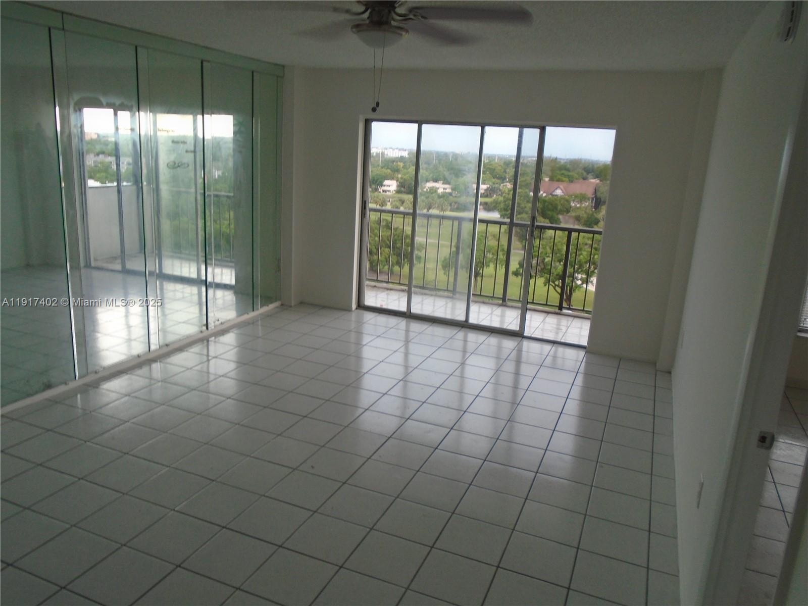 A room with white tiled floors, a ceiling fan, and sliding glass doors to a balcony — 4174 Inverrary Dr # 1004, Lauderhill FL 33319, LAUDERHILL, FL