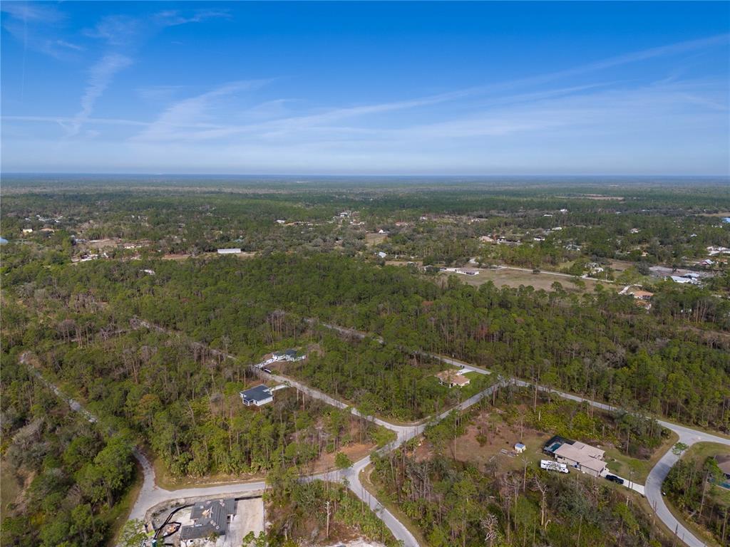 An aerial view shows a wooded residential area with scattered houses and paved roads — KAMSLER AVENUE, NORTH PORT, FL