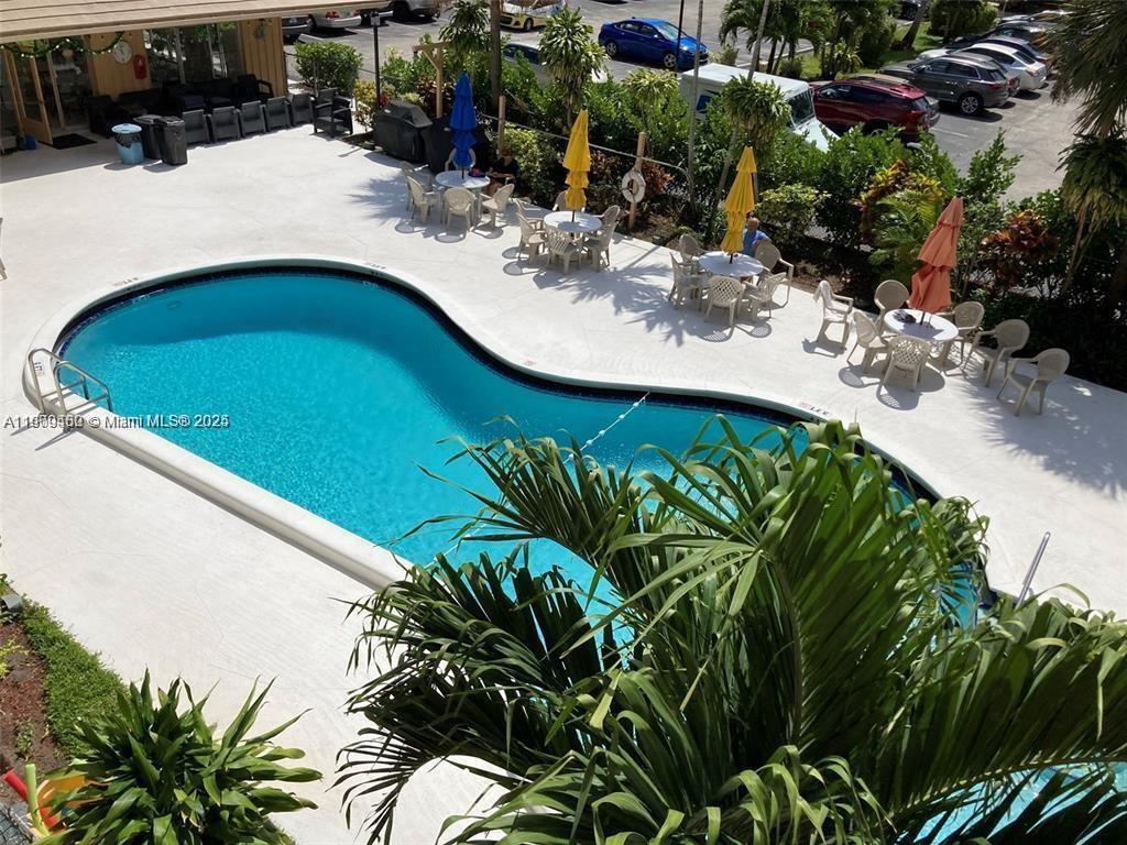 An elevated view shows a kidney-shaped swimming pool surrounded by patio tables and chairs — 2145 Pierce St # 205, Hollywood FL 33020, HOLLYWOOD, FL