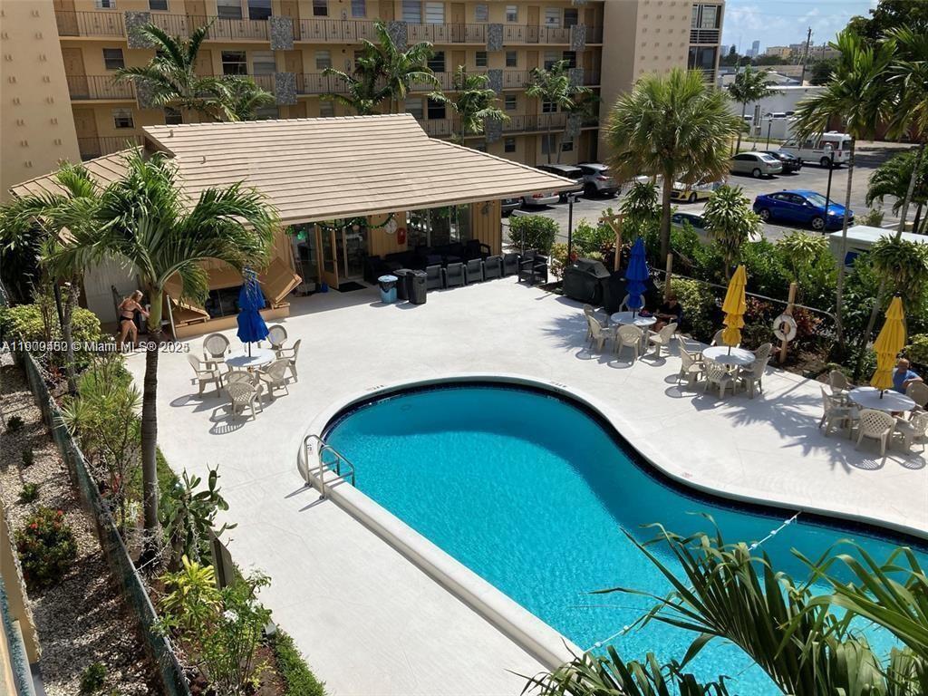 An elevated view shows a swimming pool with patio furniture and a clubhouse building — 2145 Pierce St # 205, Hollywood FL 33020, HOLLYWOOD, FL