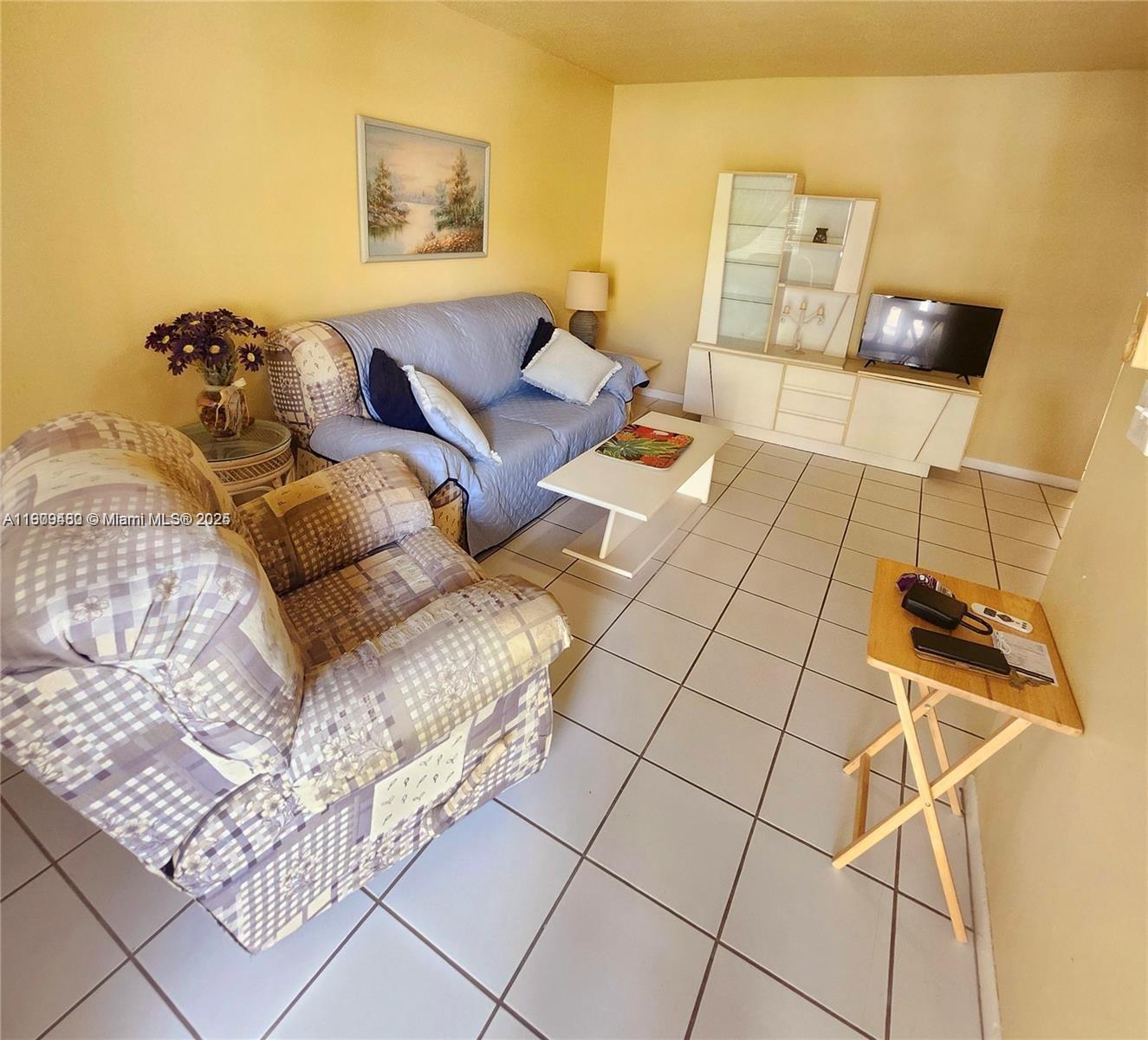 A living room features a patterned armchair, a blue sofa, and white tile flooring — 2145 Pierce St # 205, Hollywood FL 33020, HOLLYWOOD, FL
