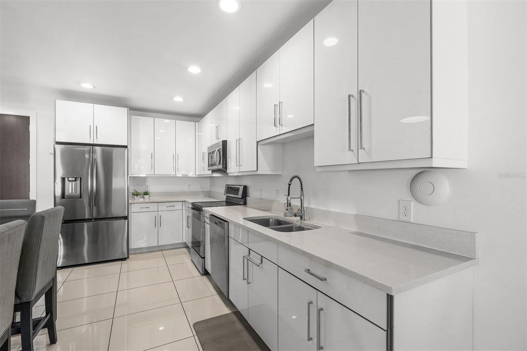 A modern kitchen features white high-gloss cabinets, stainless steel appliances, and light-colored countertops — 436 W SWOOPE AVENUE, WINTER PARK, FL