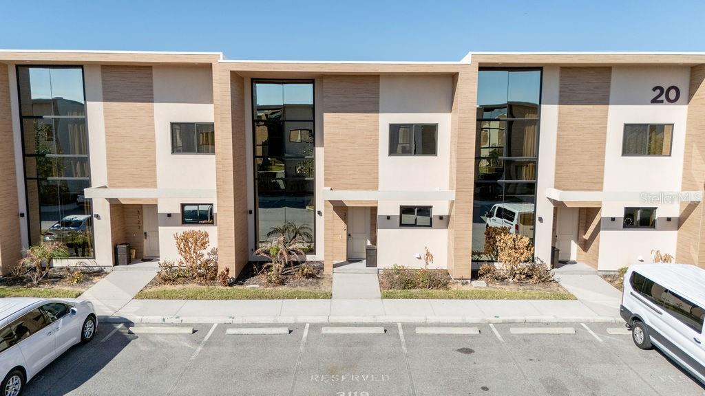 An exterior view of a modern multi-unit townhouse complex with reserved parking spaces — 3119 ROCKEFELLER WAY, KISSIMMEE, FL