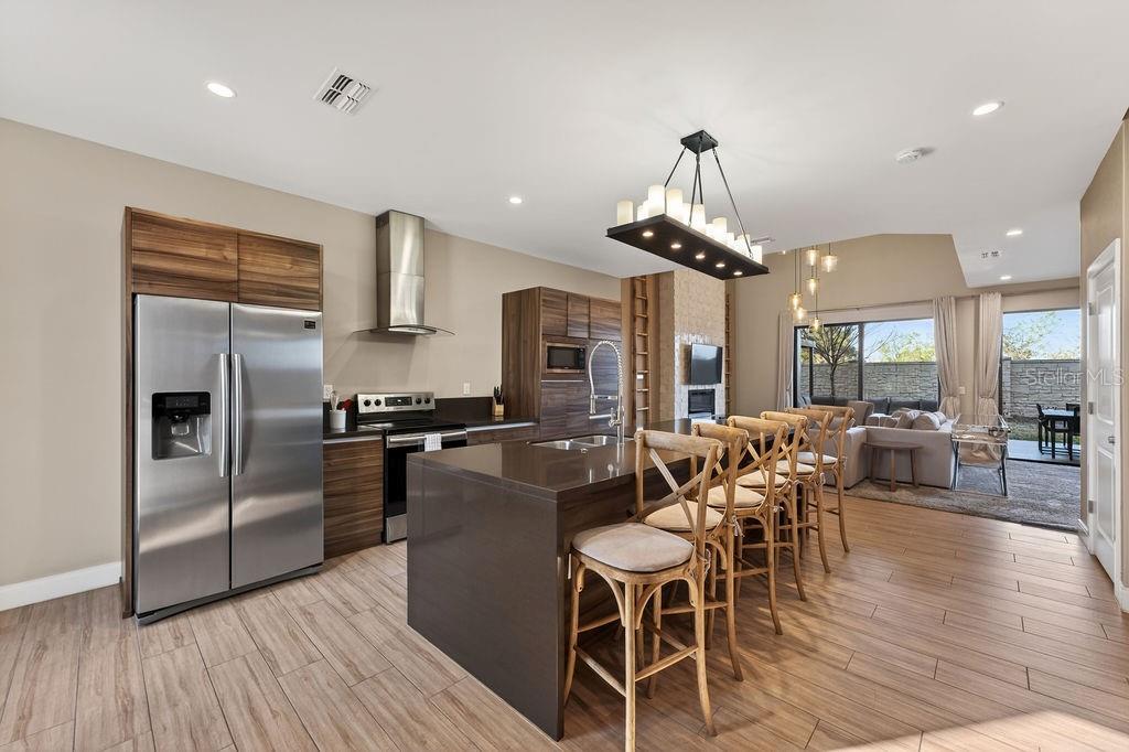 A modern kitchen with dark wood cabinets, a large island, and stainless steel appliances — 3119 ROCKEFELLER WAY, KISSIMMEE, FL
