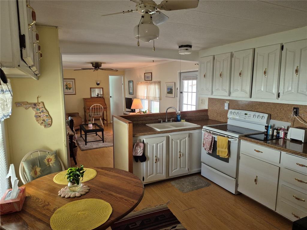 A kitchen with white cabinets and a dining table opens into a living area — 637 MISTI DRIVE, LEESBURG, FL
