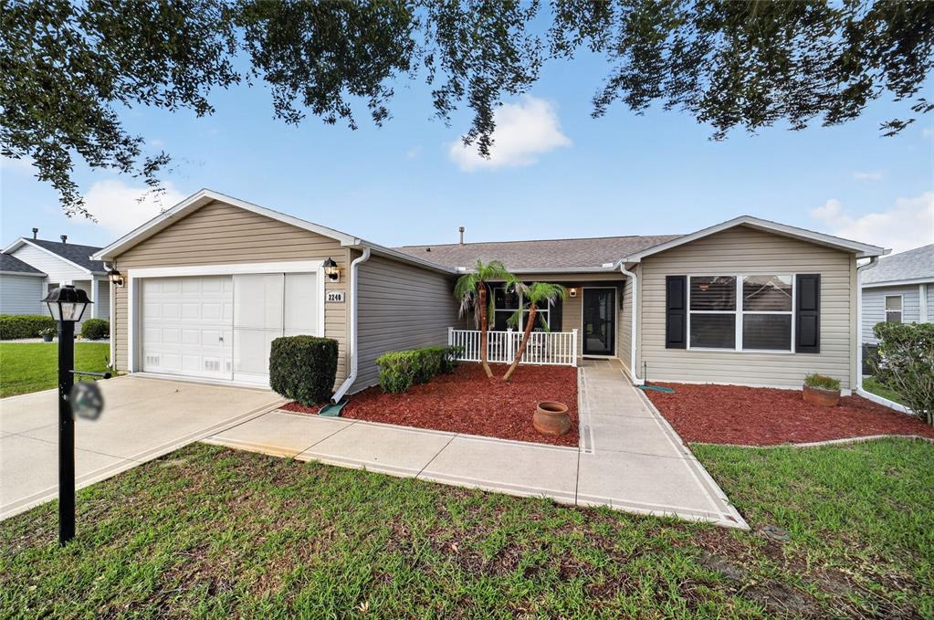 A single-story house with beige siding, a garage, and a small front porch — 2240 LOWRY ROAD, THE VILLAGES, FL