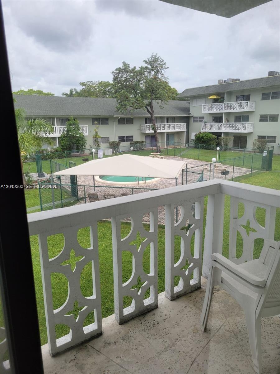 A balcony overlooks a fenced-in swimming pool area with a shade canopy and apartment buildings — 4200 NW 3rd Ct # 224, Plantation FL 33317, PLANTATION, FL