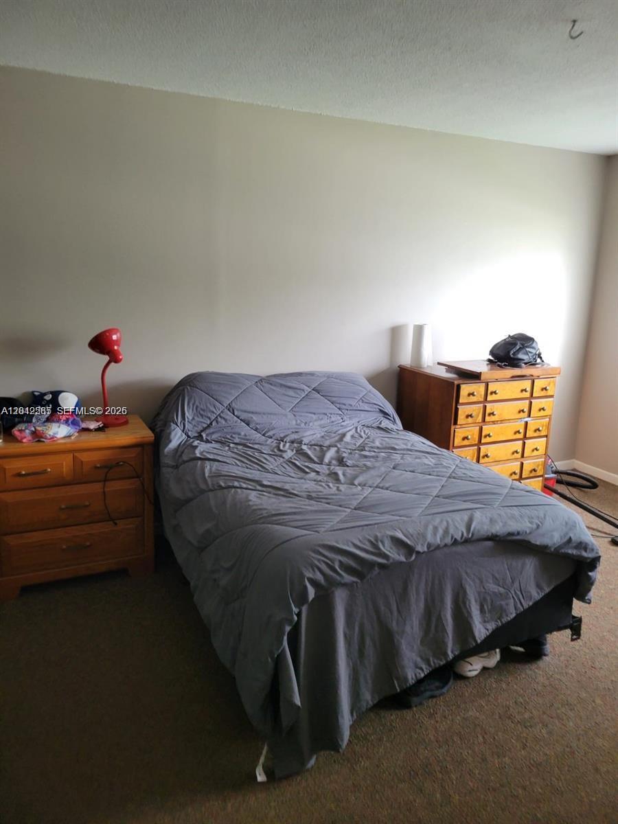 A bedroom features a bed with a gray comforter between two wooden dressers — 4200 NW 3rd Ct # 224, Plantation FL 33317, PLANTATION, FL