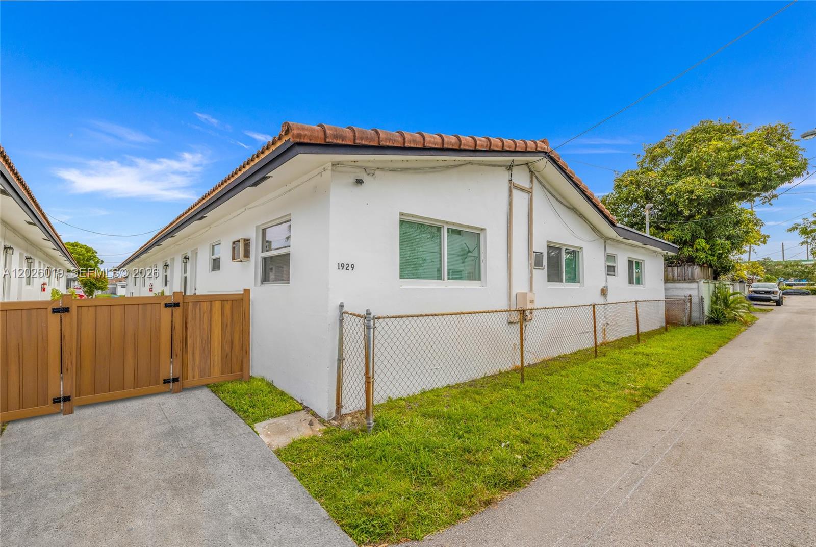 A white single-story building with a tiled roof sits beside a paved alleyway — 1927/1929 Roosevelt St, Hollywood FL 33020, HOLLYWOOD, FL