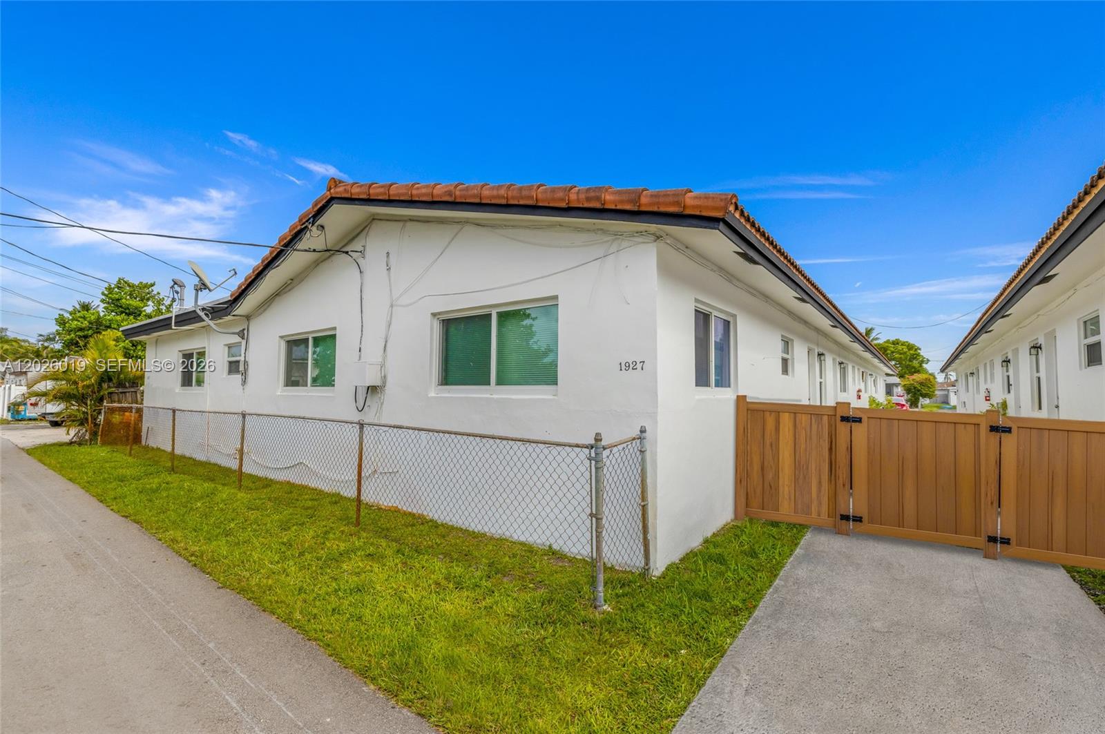 A white single-story building features a brown tile roof and a wooden gate — 1927/1929 Roosevelt St, Hollywood FL 33020, HOLLYWOOD, FL