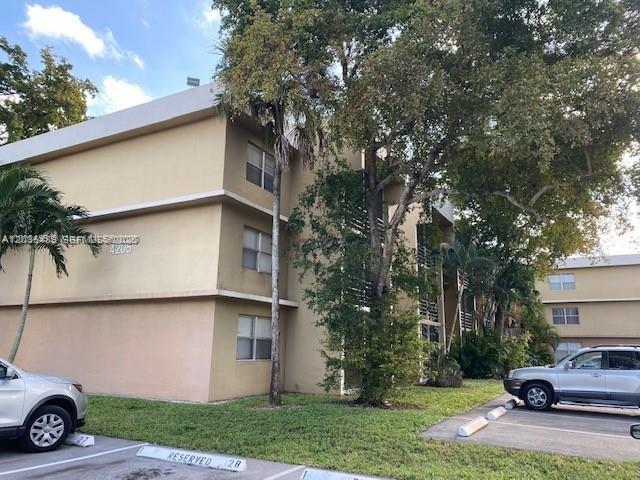 A three-story tan apartment building stands next to a parking lot with two cars — 4205 N University Dr # 208, Sunrise FL 33351, SUNRISE, FL