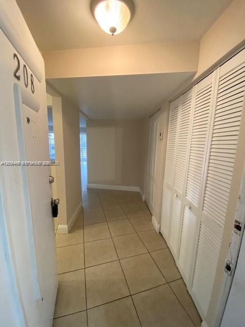 An entryway with beige tile flooring, a white door labeled 208, and louvered closet doors — 4205 N University Dr # 208, Sunrise FL 33351, SUNRISE, FL