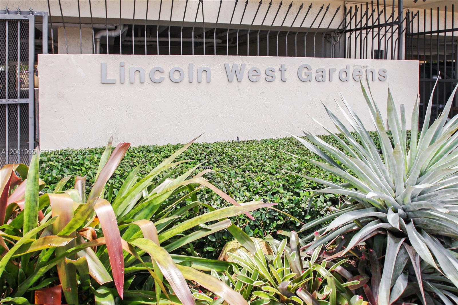 A sign reading Lincoln West Gardens stands behind a hedge and various tropical plants — 1250 Lincoln Rd # 404, Miami Beach FL 33139, MIAMI BEACH, FL