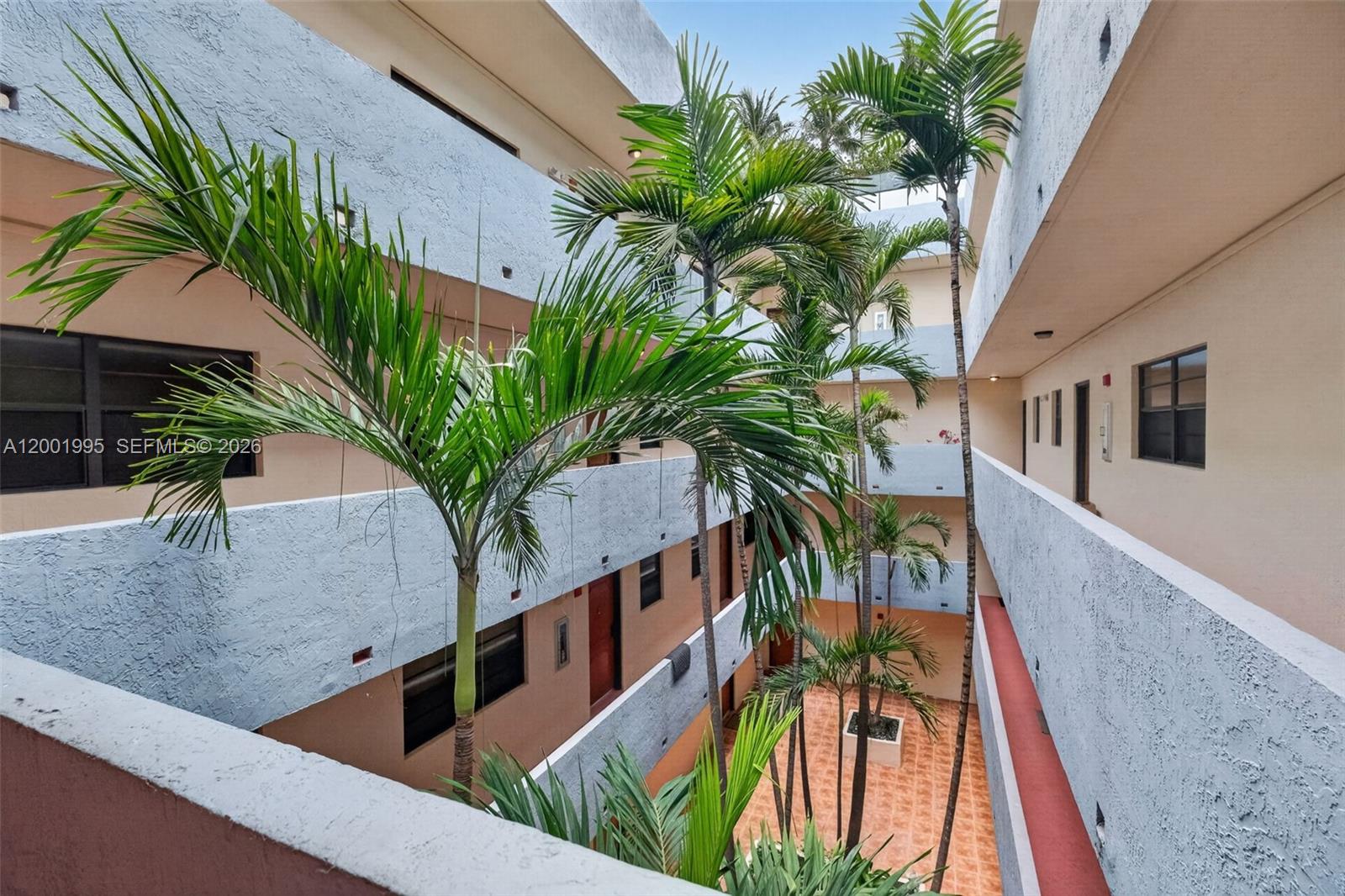 An open-air courtyard with palm trees is surrounded by multi-story apartment balconies — 1250 Lincoln Rd # 404, Miami Beach FL 33139, MIAMI BEACH, FL