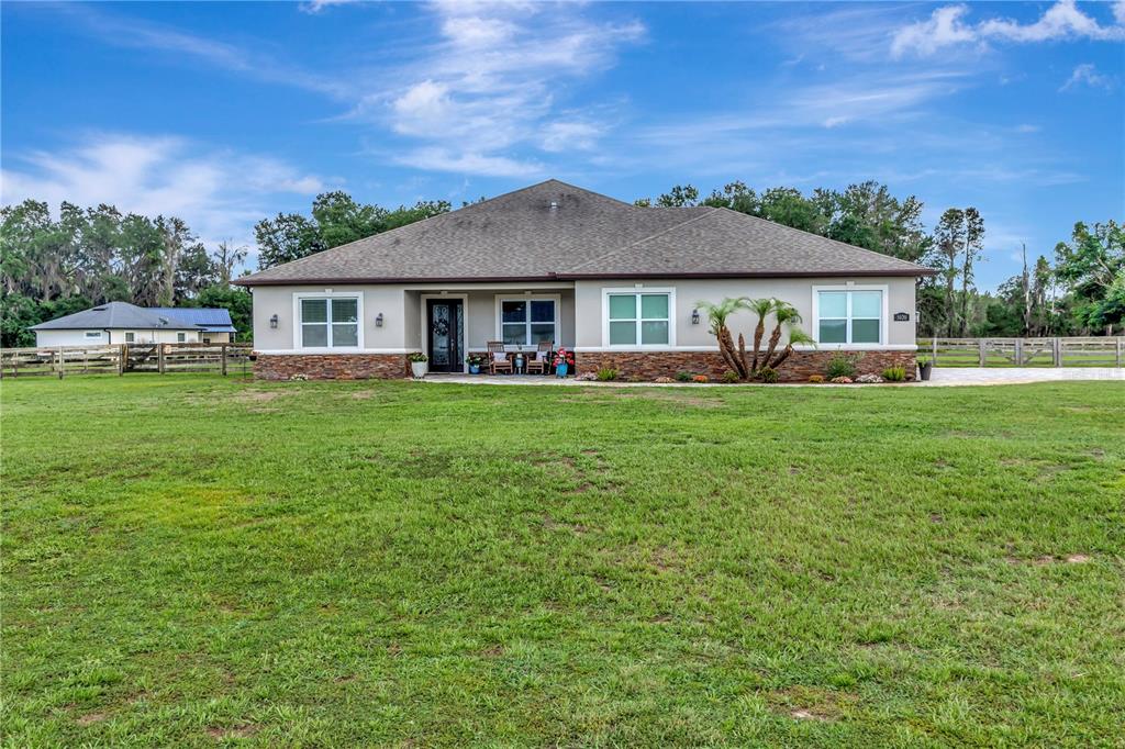 A single-story house with a stone-accented facade sits on a large, grassy rural lot — 5020 LAKESHORE RANCH ROAD, GROVELAND, FL