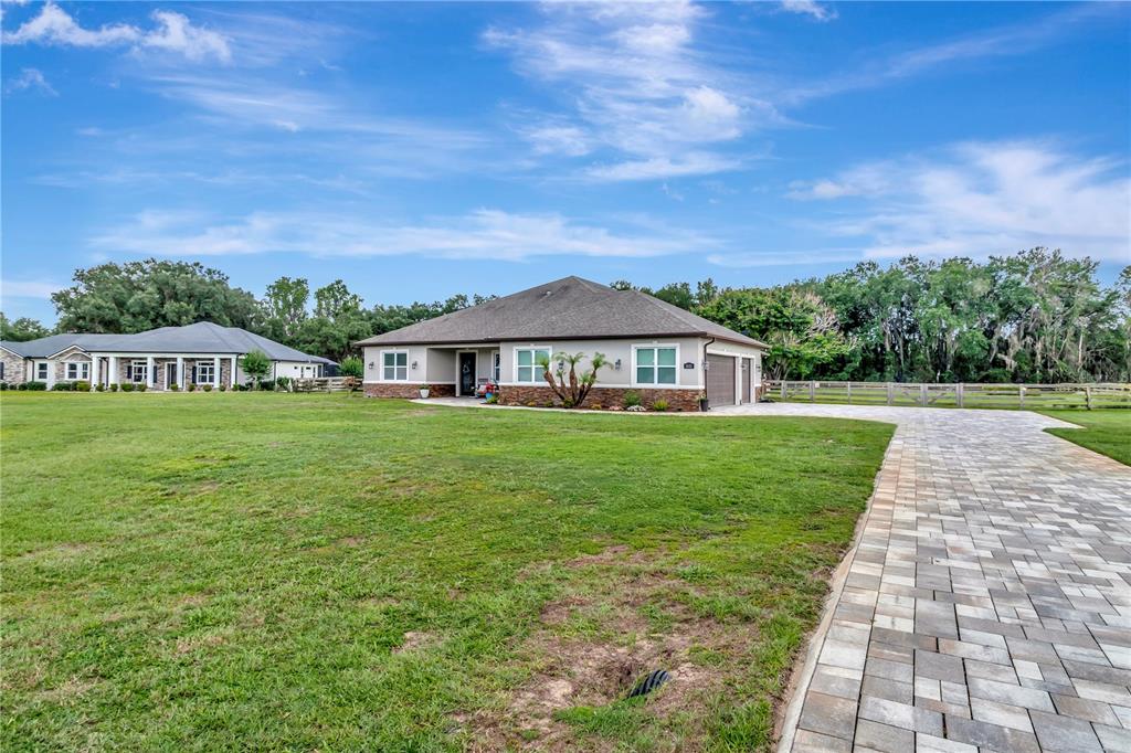 A single-story house with a stone-accented facade and a paved driveway sits on grass — 5020 LAKESHORE RANCH ROAD, GROVELAND, FL