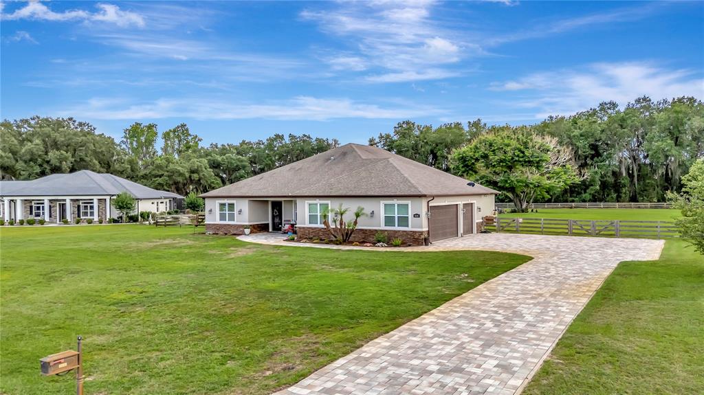 A single-story house with a paved driveway and a large lawn under a blue sky — 5020 LAKESHORE RANCH ROAD, GROVELAND, FL