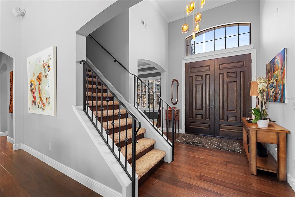 A foyer features a staircase with iron railings, wood flooring, and double front entry doors — 438 HARBOUR OAKS POINTE DRIVE, ORLANDO, FL