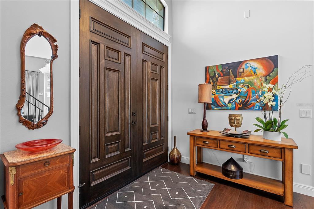 An entryway features double wooden doors, a console table, a mirror, and colorful wall art — 438 HARBOUR OAKS POINTE DRIVE, ORLANDO, FL