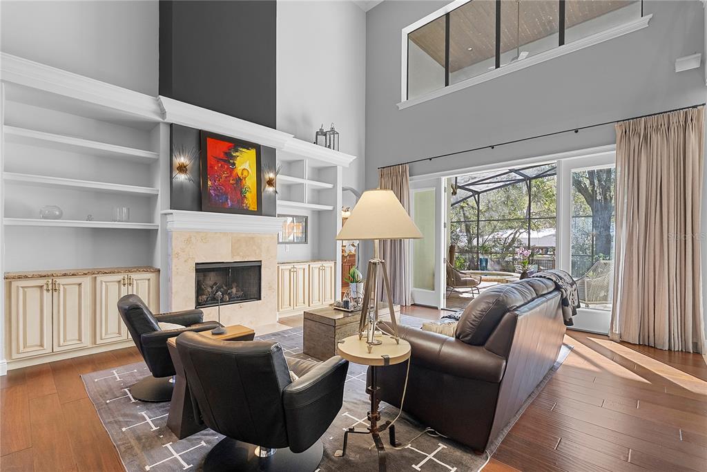 A living room features a tall fireplace, built-in shelving, leather furniture, and large glass doors — 438 HARBOUR OAKS POINTE DRIVE, ORLANDO, FL