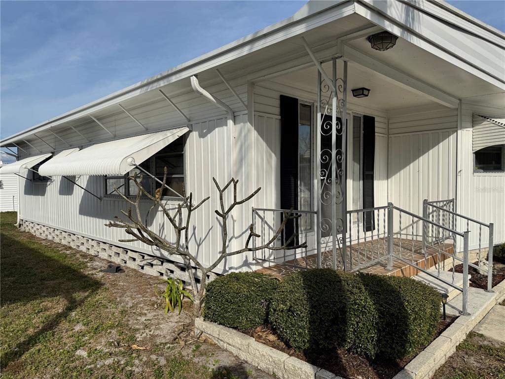 The exterior of a white mobile home features a small covered porch with metal railings — 2331 BELLEAIR ROAD UNIT 804, CLEARWATER, FL