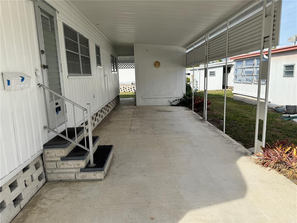 A concrete carport with a metal roof and stairs leading to a mobile home entrance — 2331 BELLEAIR ROAD UNIT 804, CLEARWATER, FL