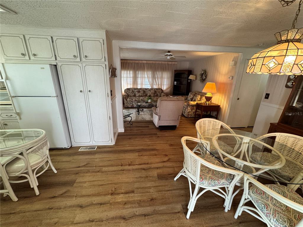 A dining area with wicker furniture leads into a living room with wood-look flooring — 2331 BELLEAIR ROAD UNIT 804, CLEARWATER, FL