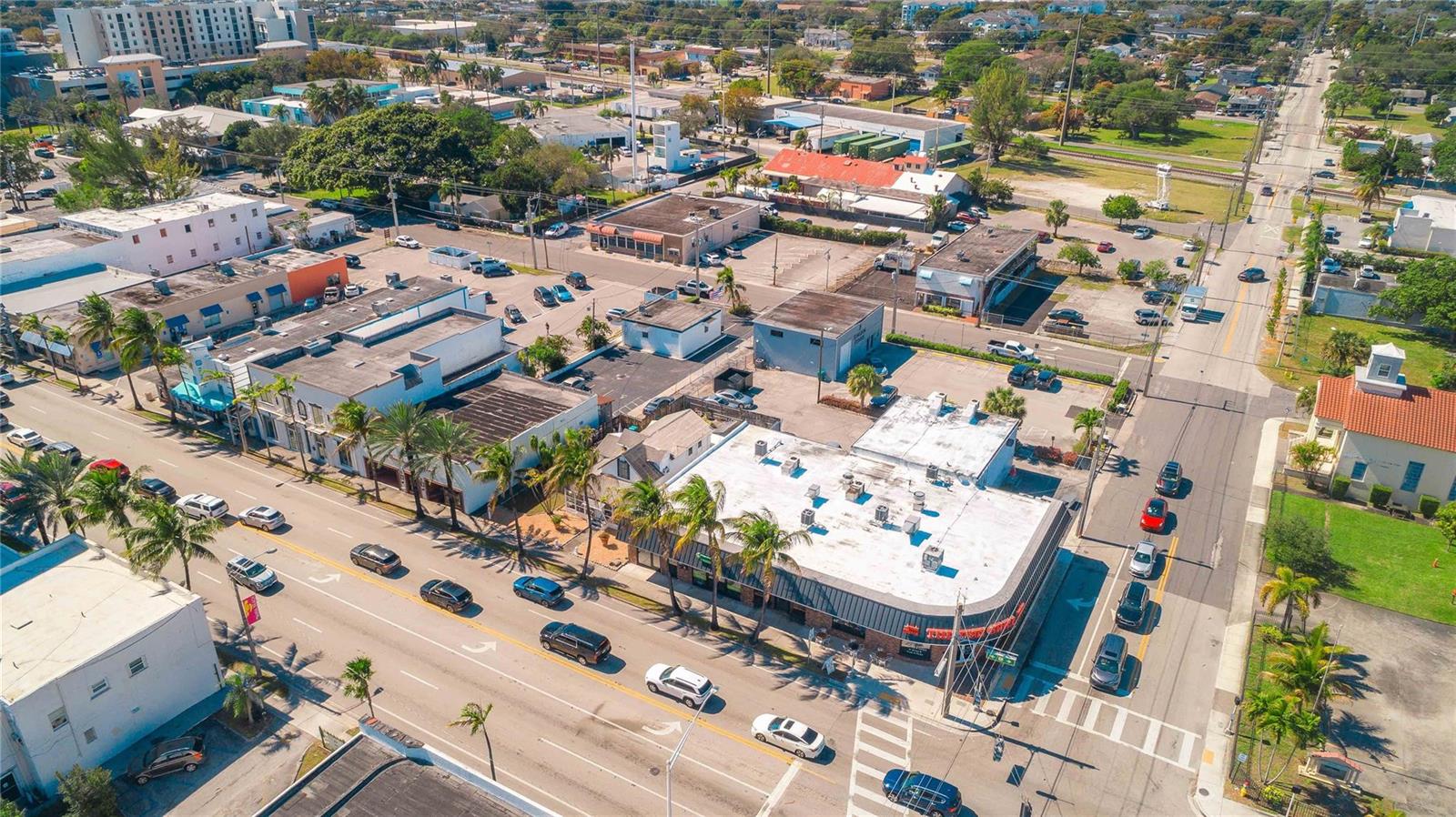 An aerial view shows a commercial street with buildings, parking lots, and surrounding palm trees — 49 N Federal Highway, Dania Beach FL 33004, DANIA BEACH, FL