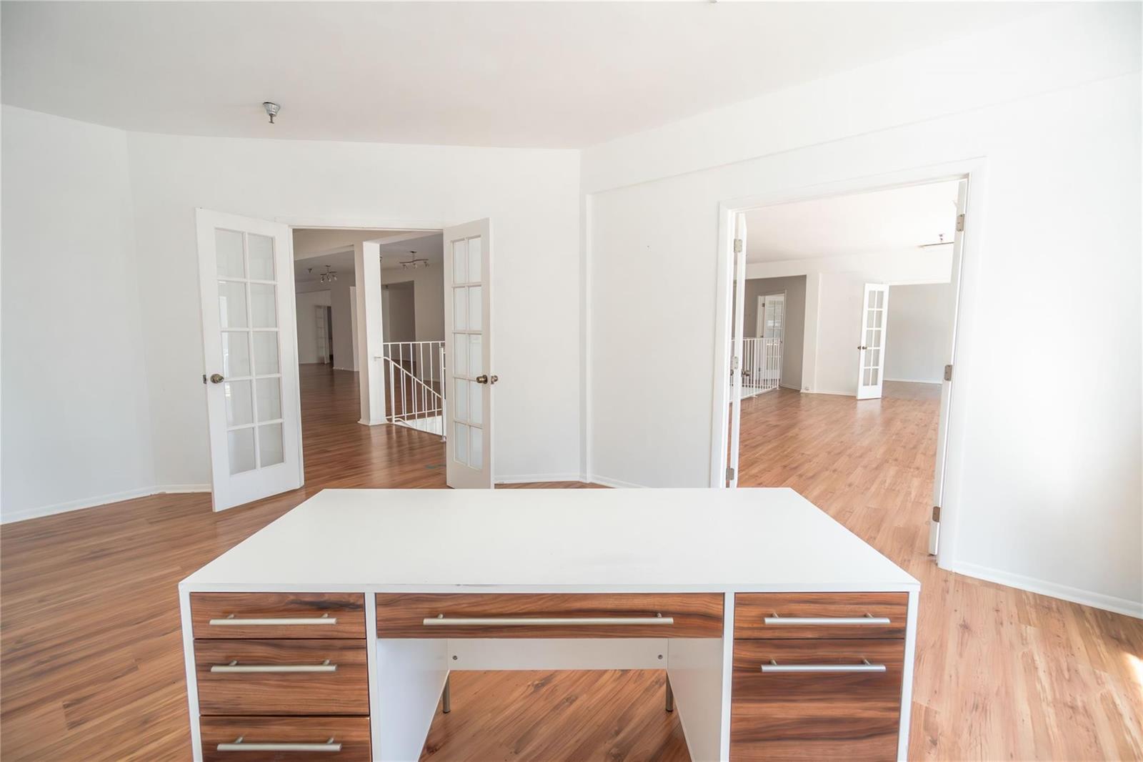 A white desk sits in a room with wood-look flooring and two open French doorways — 49 N Federal Highway, Dania Beach FL 33004, DANIA BEACH, FL
