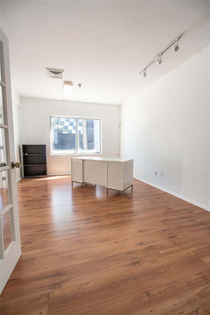 An office room features wood-look flooring, white walls, a desk, and a black bookshelf — 49 N Federal Highway, Dania Beach FL 33004, DANIA BEACH, FL