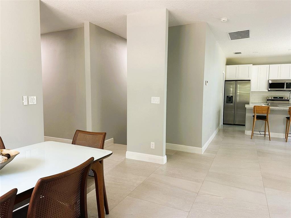 A dining area with a white table and chairs opens into a kitchen with stainless appliances — 358 CHEROKEE AVENUE, HAINES CITY, FL