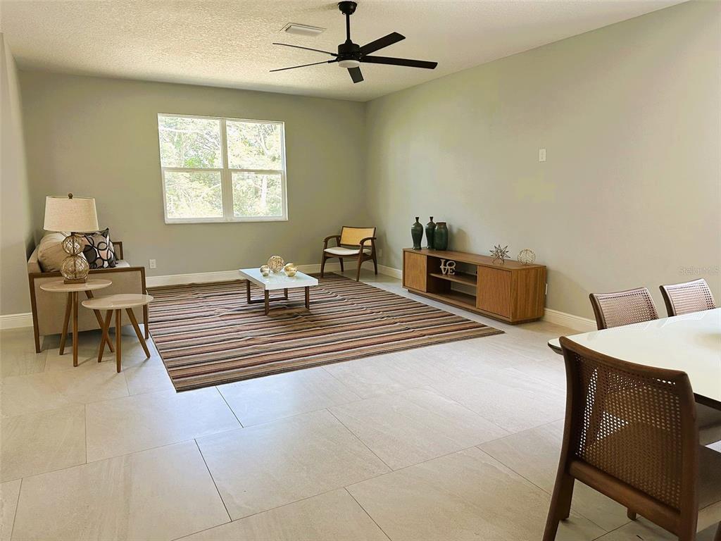A living room with light-colored tile floors, a striped area rug, and a ceiling fan — 358 CHEROKEE AVENUE, HAINES CITY, FL