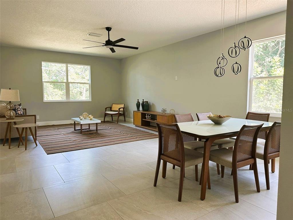 A combined living and dining area features tile flooring, a ceiling fan, and large windows — 358 CHEROKEE AVENUE, HAINES CITY, FL