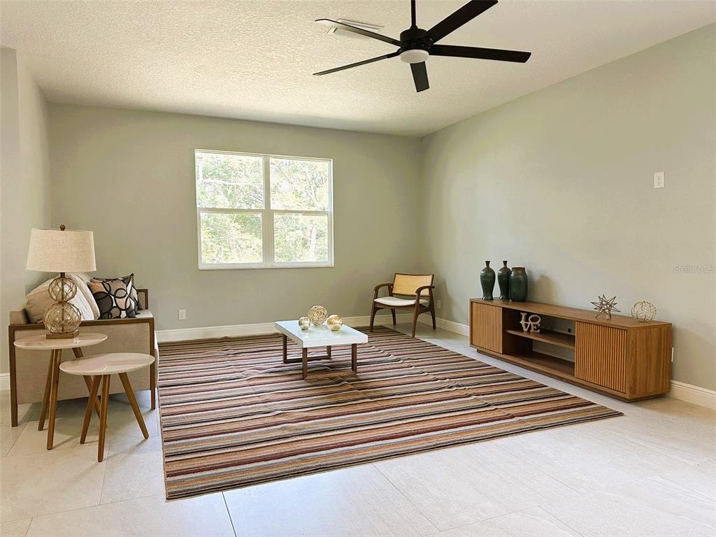A living room features a striped rug, a wooden media console, and a ceiling fan — 358 CHEROKEE AVENUE, HAINES CITY, FL